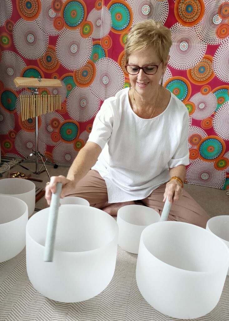Photo of Maia Martin playing crystal bowls for sound healing session.