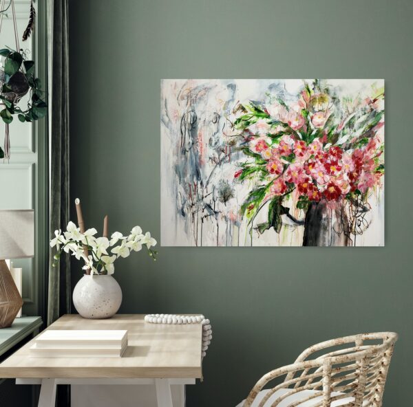 Spring's Grace - This abstracted mixed media artwork portrays a vase of red and pink luscious flowers sitting amidst luscious green foliage. The abstract background adds interest to the overall composition of the painting. This painting is hanging on a green wall behind a desk and cane chair.