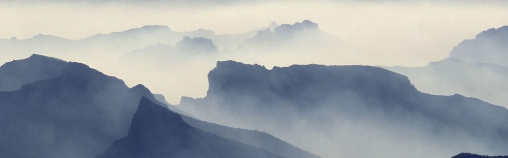 Photo of pale mountain in fog.